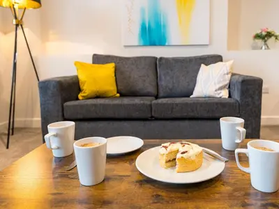 a table with a plate of cake and cups of coffee at Perfectly located 2 bed townhouse in Shrewsbury - Pass the Keys in Shrewsbury