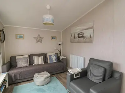 a living room with a couch and a chair at Chalet 64 in Tywyn