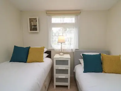 a bedroom with two beds and a lamp on a night stand at Chalet 64 in Tywyn
