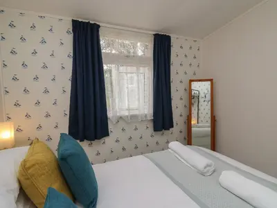 a bedroom with a bed and a window at Chalet 64 in Tywyn