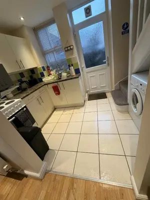 a kitchen with a white tiled floor and a washing machine at Hill View Cottage in Bala