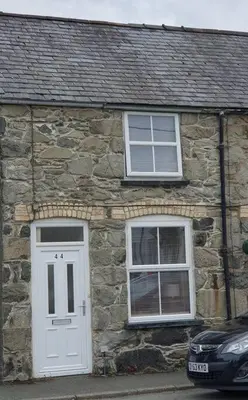 a stone house with a white door and two windows at Hill View Cottage in Bala