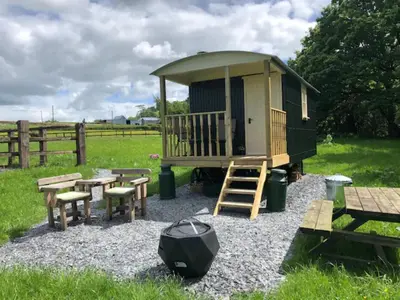 a cabin with a table and benches and a fence at Shepherds Hut at The Retreat in Oswestry