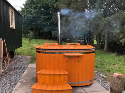 a wooden barrel with a stove in a yard at Shepherds Hut at The Retreat in Oswestry