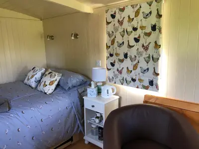 a small bedroom with a bed and a chair at Shepherds Hut at The Retreat in Oswestry