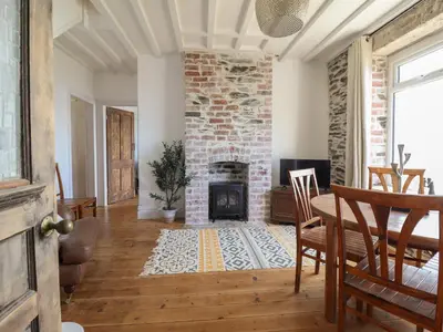 a living room with a brick fireplace and a table and chairs at Windycroft in Barmouth