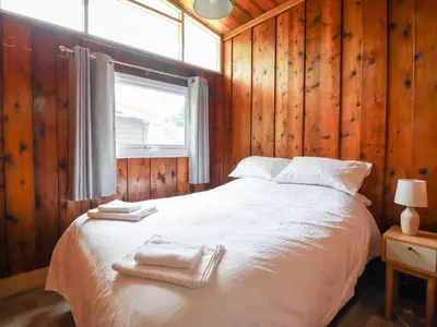 a bedroom with a bed with wooden walls and a window at Chalet 2 in Machynlleth