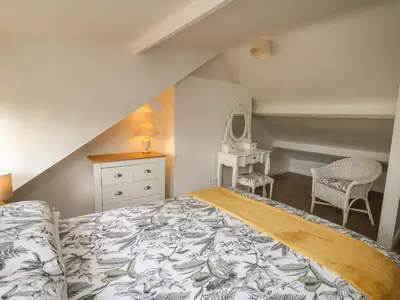 a attic bedroom with a bed and a chair at Rowan Cottage in Builth Wells