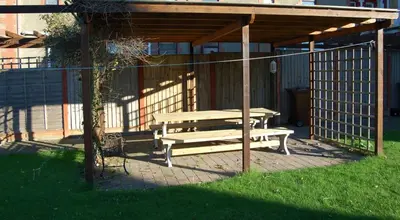 a picnic shelter with a picnic table in the grass at Angorfa family holiday home with games room in Tywyn