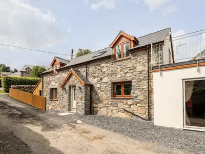 a stone house on a gravel road at Llys Tirion in Bala