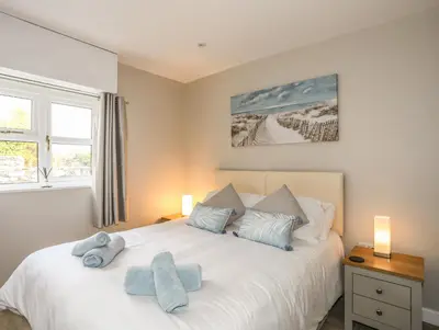a bedroom with a white bed with blue towels on it at Bryn Y Mor in Tywyn