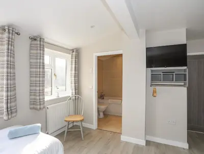 a bedroom with a bed and a tv and a bathroom at Bryn Y Mor in Tywyn