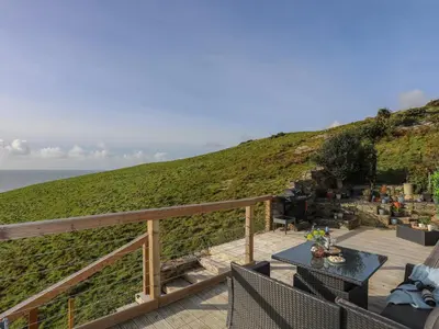 a patio with a table and chairs and the ocean at Bryn Y Mor in Tywyn