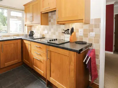 a kitchen with wooden cabinets and a black counter top at 24 Dolithel in Tywyn