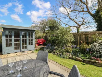 a patio with a table and chairs in a garden at 24 Dolithel in Tywyn
