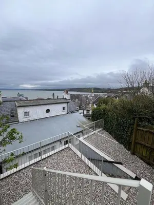 a view of a house with a fence and stairs at Efail Fach in New Quay