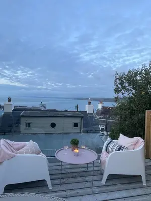 a patio with two white chairs and a table at Efail Fach in New Quay