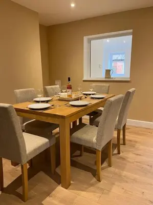 a wooden table with chairs and a bottle of wine at Beautiful mid wales cottage in Garth