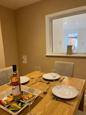 a wooden table with a bottle of wine and glasses at Beautiful mid wales cottage in Garth