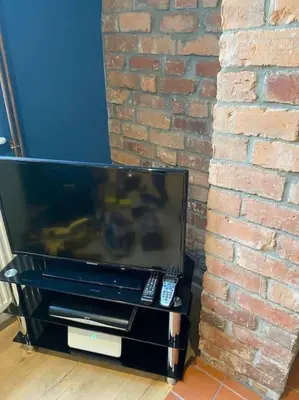 a flat screen tv sitting next to a brick wall at Beautiful mid wales cottage in Garth