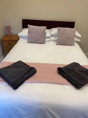 a white bed with two black towels on it at Beautiful mid wales cottage in Garth