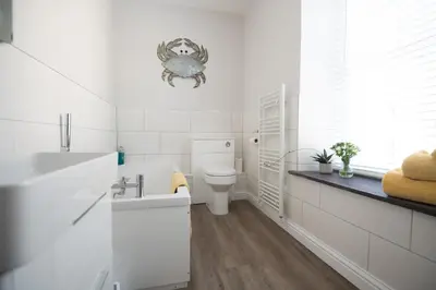 a white bathroom with a toilet and a sink at Loyalty in New Quay