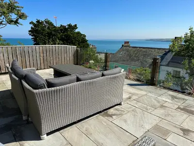 a wicker couch sitting on top of a patio at Loyalty in New Quay