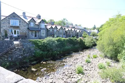 a river in front of a row of houses at Dolafon in Llanbedr