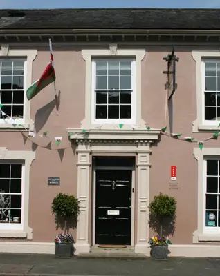 a pink building with a black door and a flag at The New White Lion in Llandovery