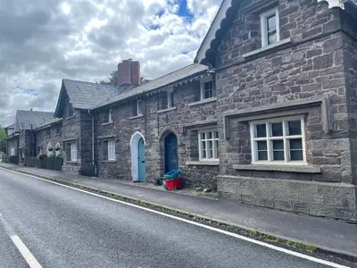 a stone building with a blue door on a street at Yew Tree Cottage, 3 bedroom, 4 Church Row Defynnog in Devynock