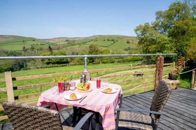 a table and two chairs on a wooden deck at Ty Grug Pods in Bryngwyn