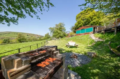 a grill with hot dogs on it in a yard at Ty Grug Pods in Bryngwyn