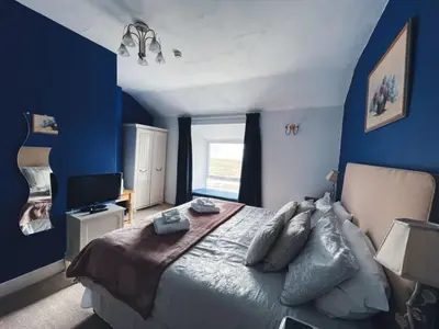 a bedroom with a large bed with blue walls at Wavecrest in Barmouth