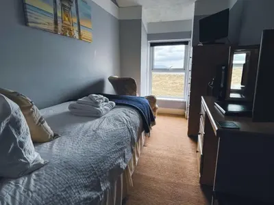 a bedroom with a bed and a chair and a window at Wavecrest in Barmouth