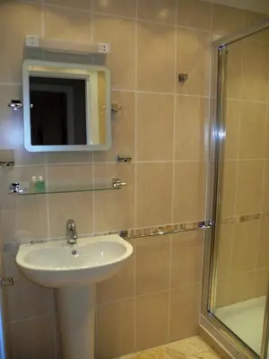 a bathroom with a sink and a shower with a mirror at Wavecrest in Barmouth