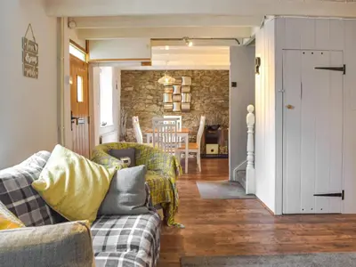 a living room with a couch and a dining room at Penlan Cottage in Cwrt-newydd