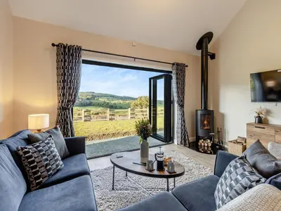 a living room with a blue couch and a large window at The Lara - Uk45019 in Mochdre