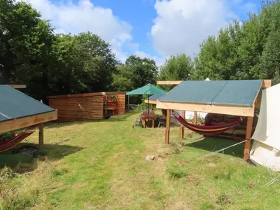 a yard with a hammock and a house at Dingly Dell 3 x bell tents in Cemmaes