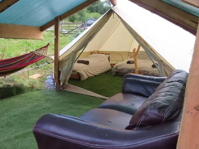 a tent with two beds and a hammock in a field at Dingly Dell 3 x bell tents in Cemmaes