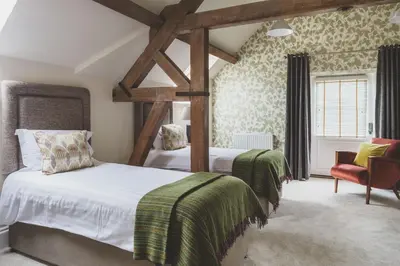 a bedroom with two beds and a chair at The Clive Arms in Ludlow