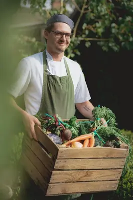 a man holding a wooden box filled with vegetables at The Clive Arms in Ludlow