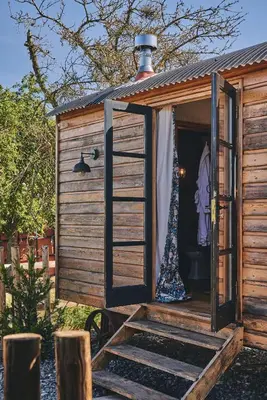 a wooden outhouse with a door and a window at Curious Calf in Leominster
