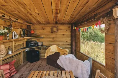 a wooden cabin with a table and a window at Curious Calf in Leominster