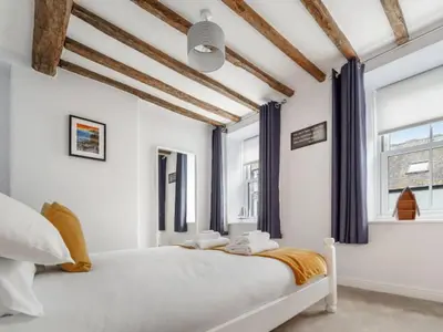 a bedroom with a large white bed with blue curtains at Characterful 3 Bedroom Cottage in Aberystwyth