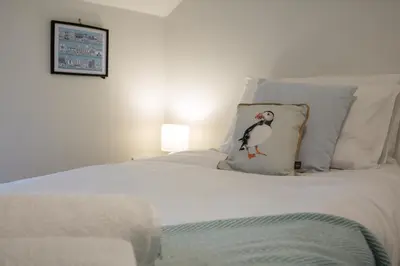 a white bed with a penguin pillow on it at Relaxing Town Centre House - Perfect for Exploring in Shrewsbury