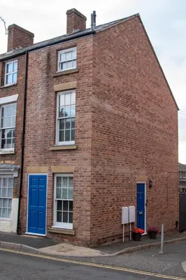 a brick building with blue doors on a street at Relaxing Town Centre House - Perfect for Exploring in Shrewsbury