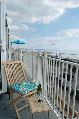 a deck with a chair and a table with wine glasses at Driftwood Designer Apartment in Tywyn