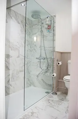 a shower with a glass door in a bathroom at Driftwood Designer Apartment in Tywyn