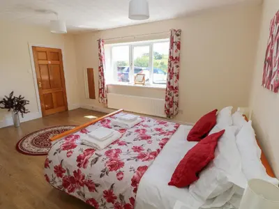 a bedroom with a bed with red pillows and a window at Hillside Lodge in Llandrindod Wells