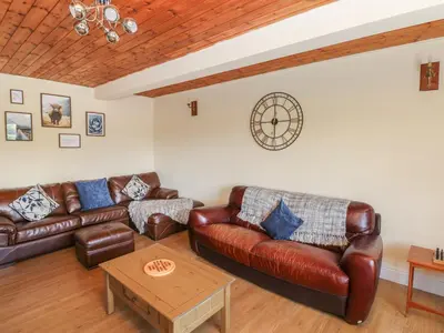 a living room with leather couches and a table at Hillside Lodge in Llandrindod Wells